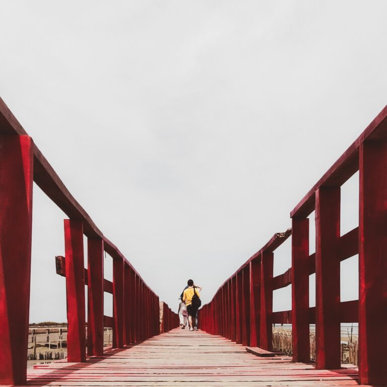 A man wearing yellow t-shirt walk on red bridge