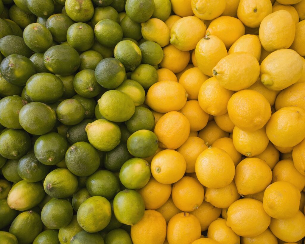 Lemons and limes, citrus fruits, divided into two piles, contrasting in colour.