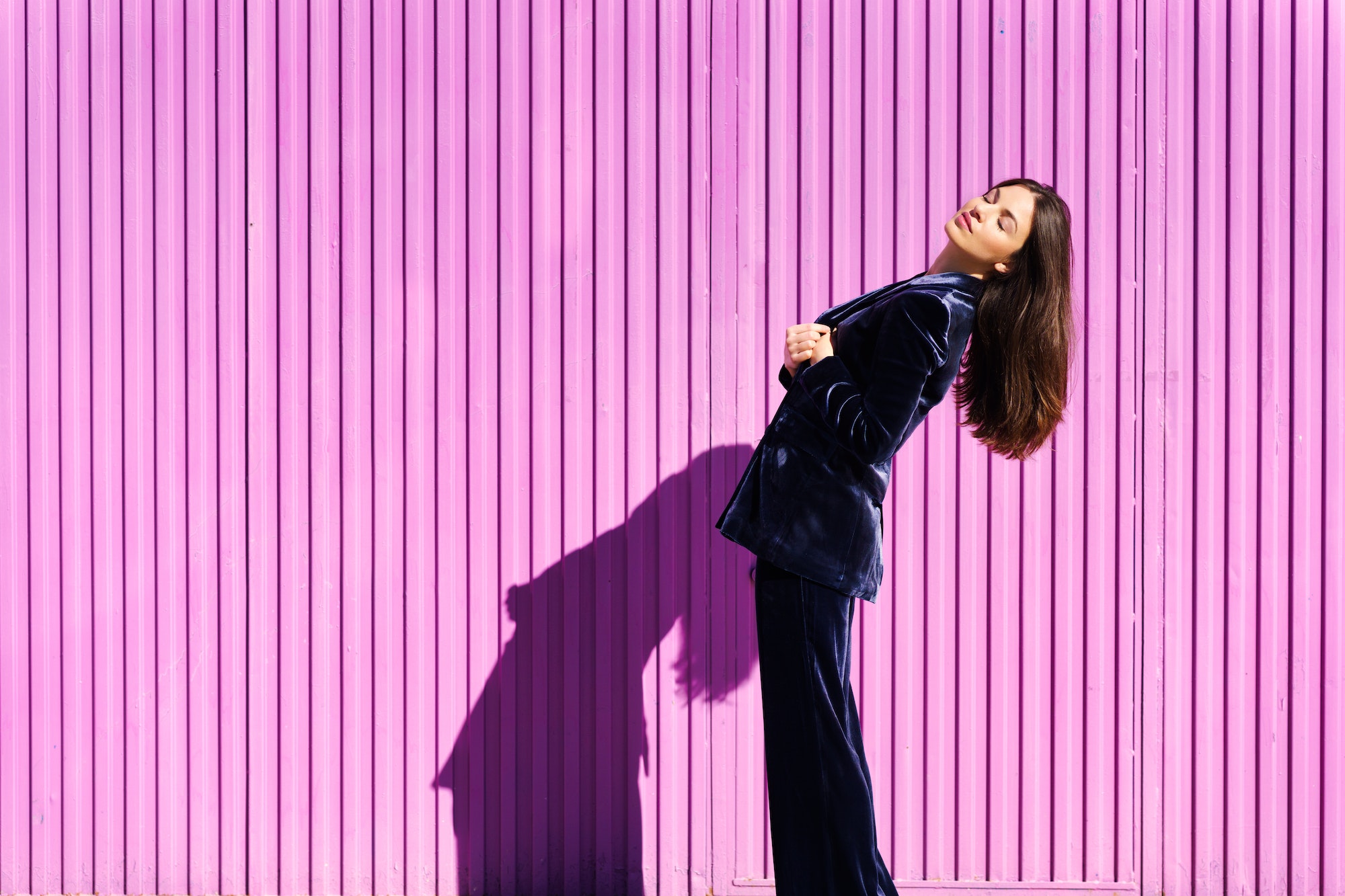 Woman wearing blue suit posing near pink shutter