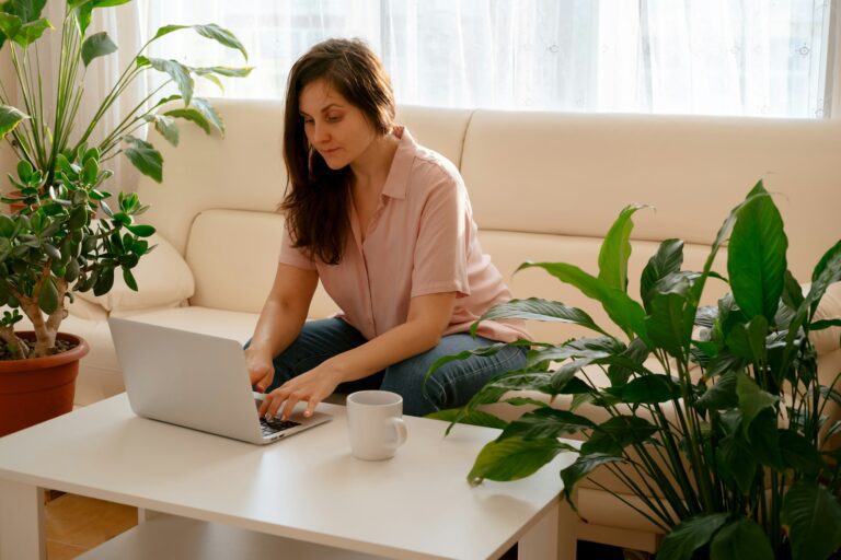 Young beautiful woman working with computer indoor in a light room with a lot of plants.